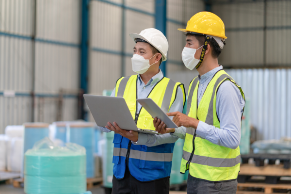 2. Deux auditeurs en uniforme effectuent un audit d'usine avec des tablettes à la main