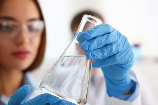 3. A laboratory scientist wearing blue gloves and looking at a flask 