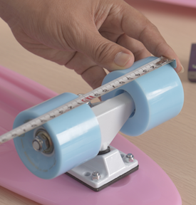 An inspector sizing the wheels of a pink skateboard